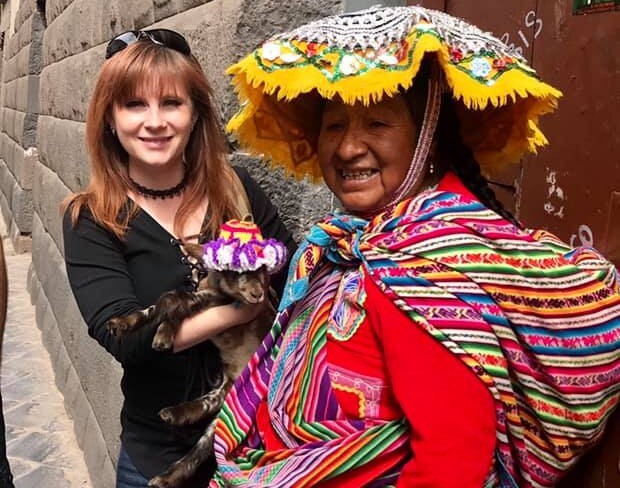 Jayce holding a baby goat beside a peruvian