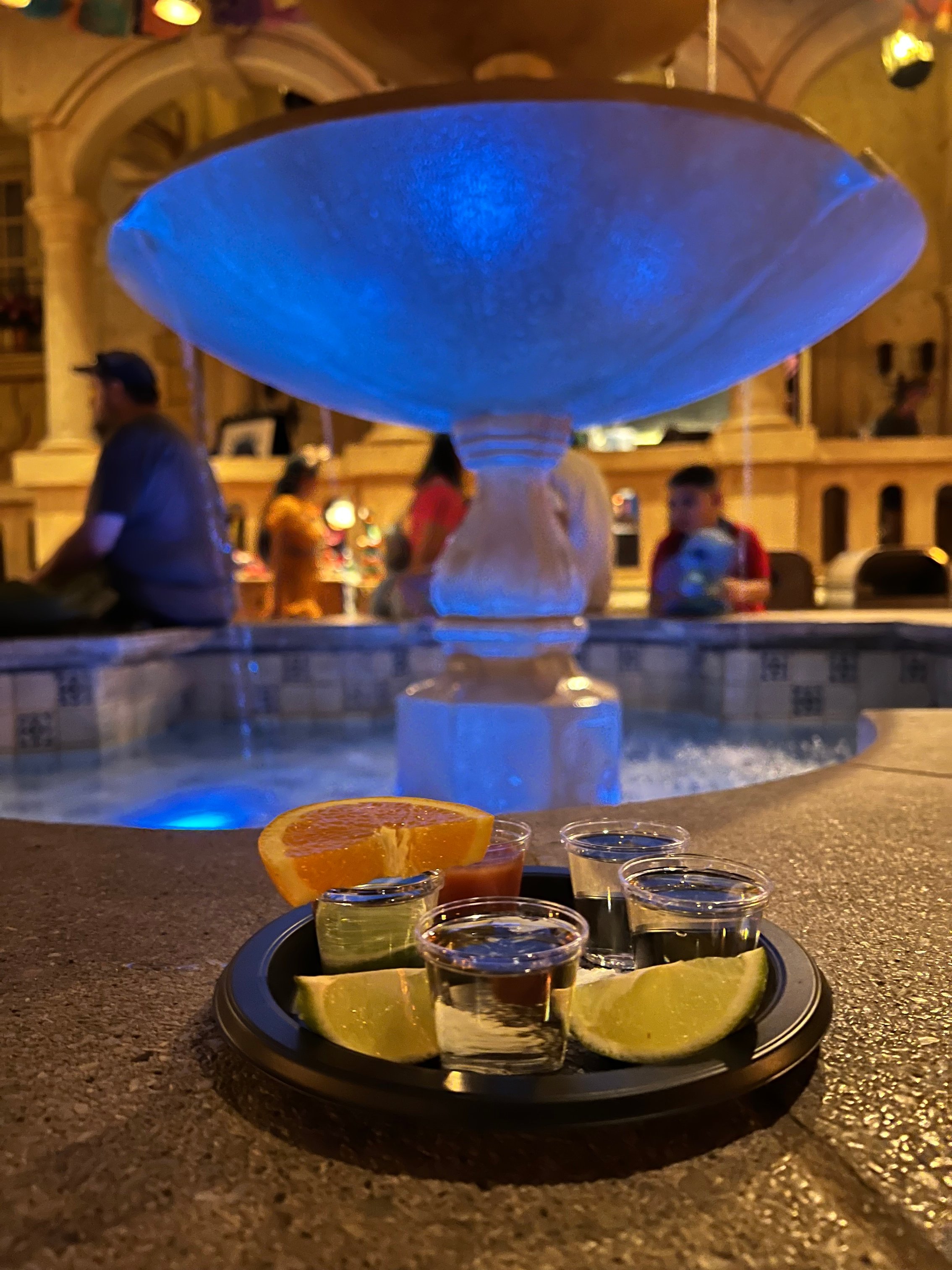 Tequilla shots sitting in front of an outdoor fountain