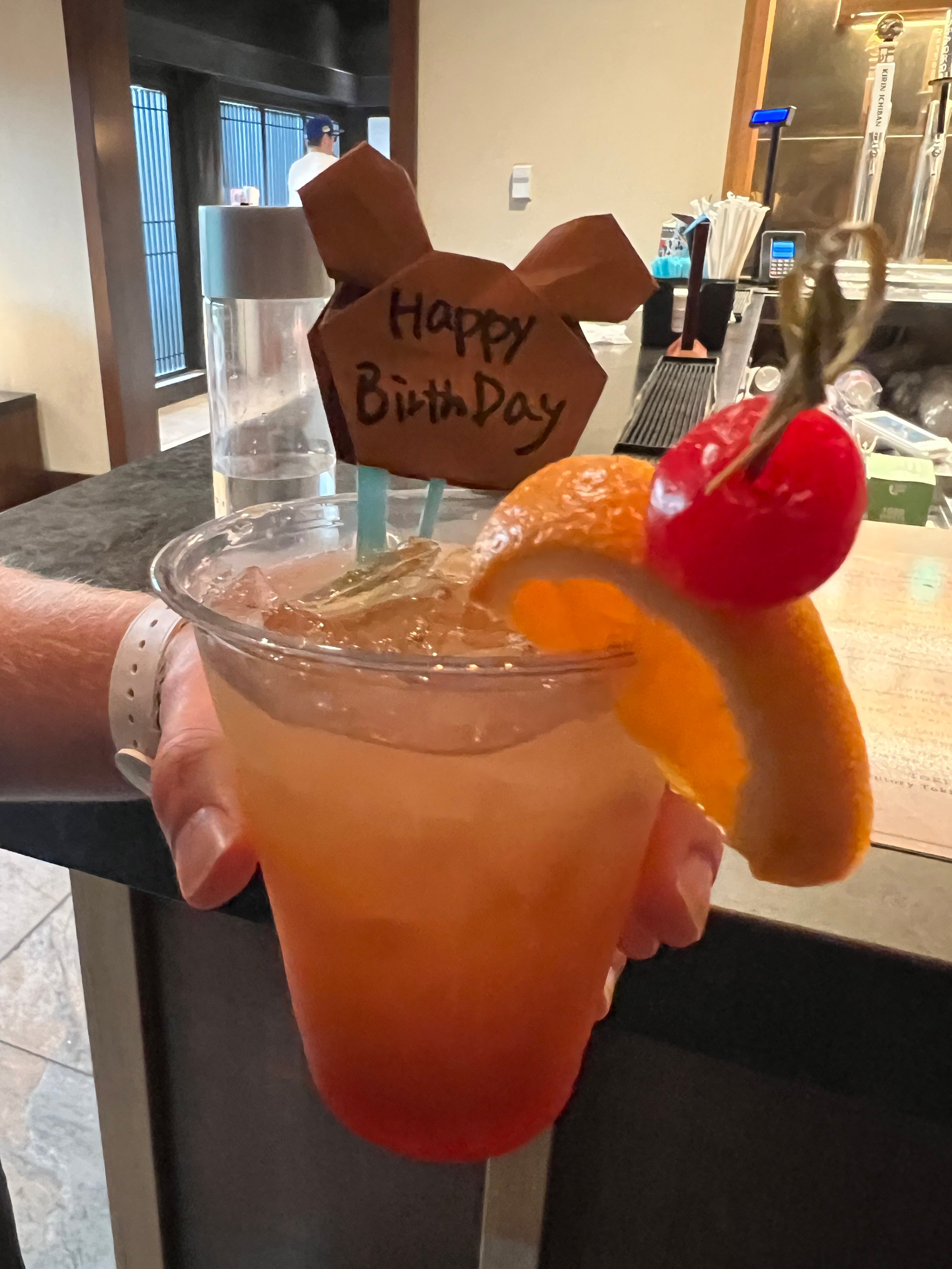 A cocktail with a fruit garnish and a happy birthday sign