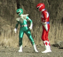 Gif of 2 guys dressed in suits that look like Power Rangers shrugging.