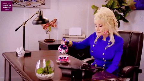 Dolly Parton winking and pouring tea into a tea cup.